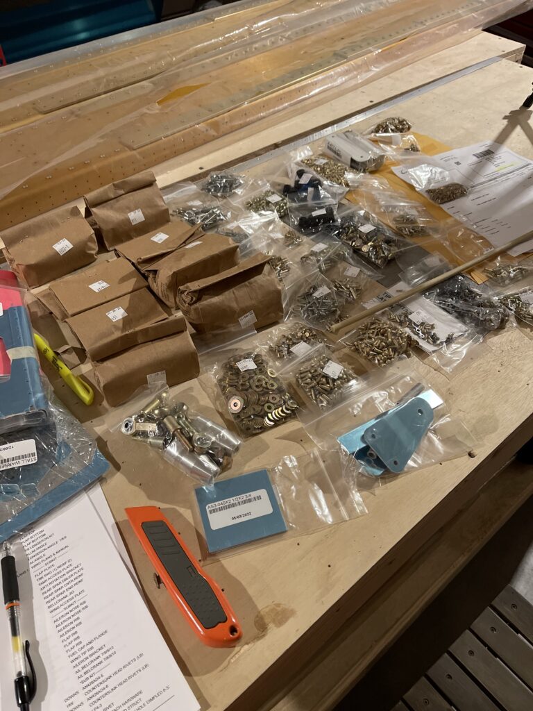 Various bags of hardware on a wooden table.